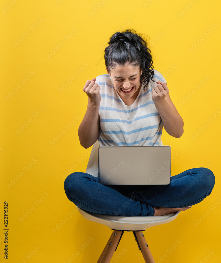 年轻女子在黄色背景下使用笔记本电脑