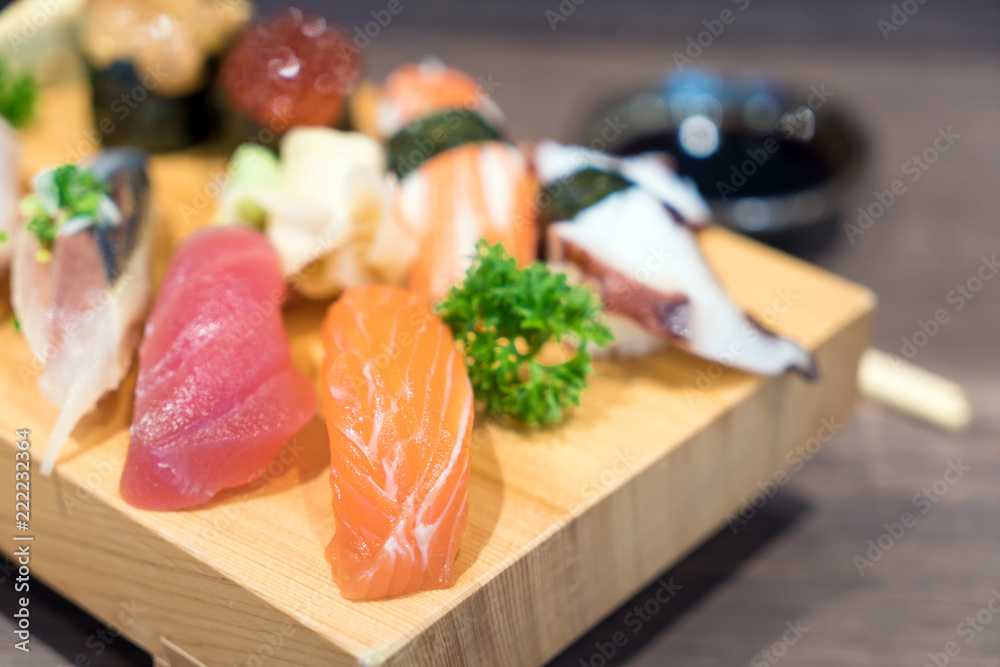 近景寿司和生鱼片混合在黑色木桌上的木板上。日本食物。