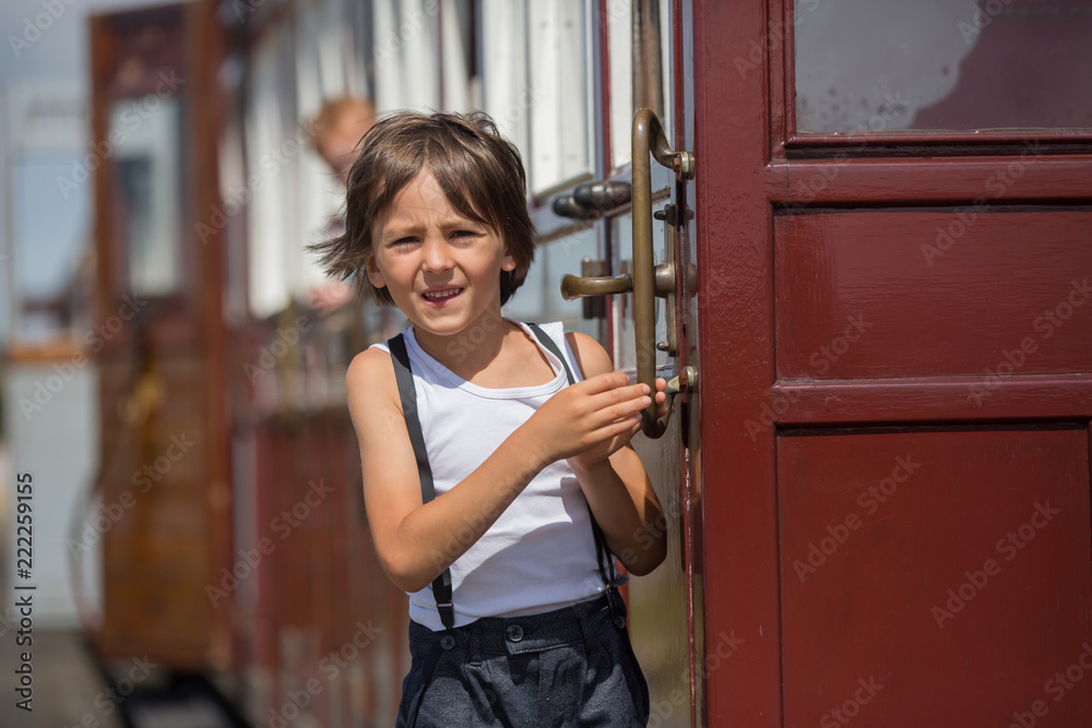 Beautiful child, dressed in vintage clothes, enjoying old steam train on a hot summer day