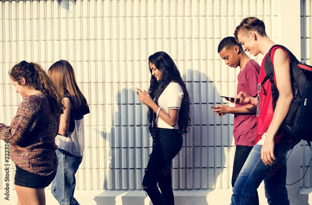Group of young teenager friends walking home after school using smartphones addiction concept