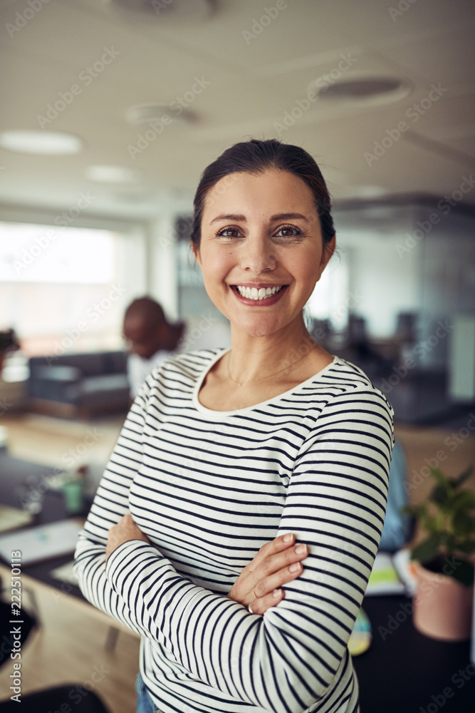 微笑的女商人双臂交叉站在办公室里