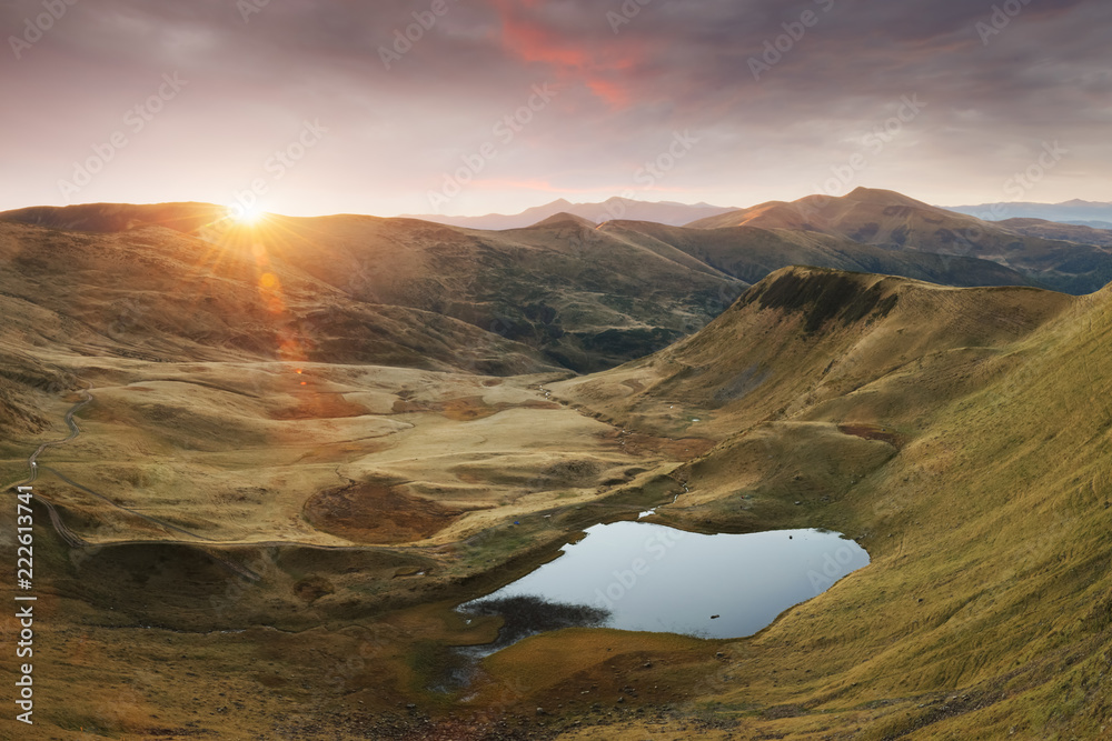 Mountain lake on sunrise time. Picturesque autumn landscape with sun in morning sky, Carpathian moun