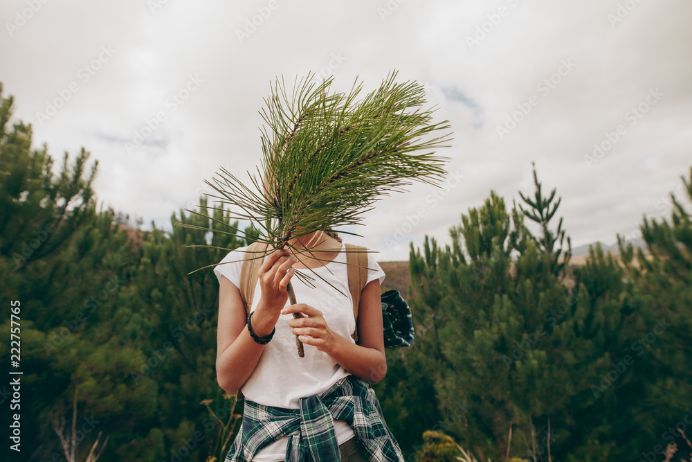 女旅行者拿着树枝遮住她的脸