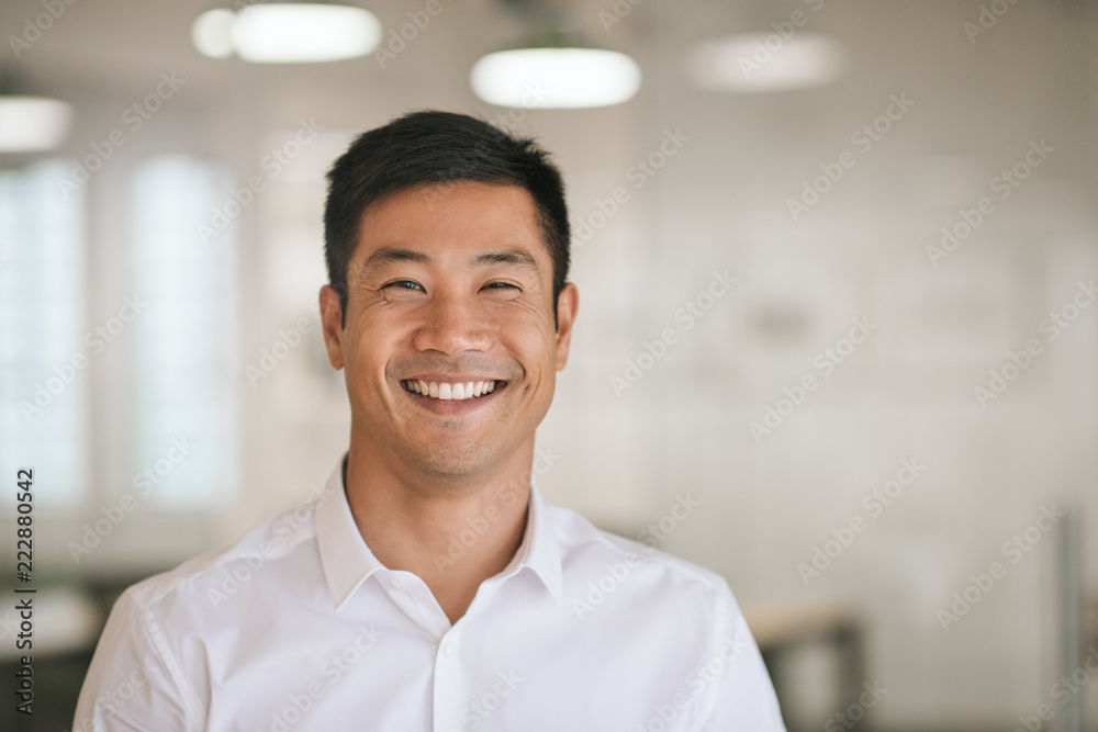 年轻的亚洲商人站在办公室里自信地微笑