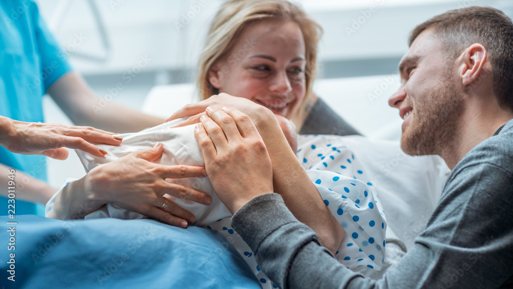 在医院里，助产士把新生儿交给母亲抱着，父亲慈爱地拥抱B
