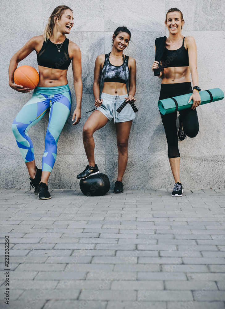 三名穿着训练服的女性锻炼后站在户外