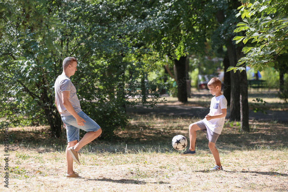 小男孩和爸爸在户外踢足球