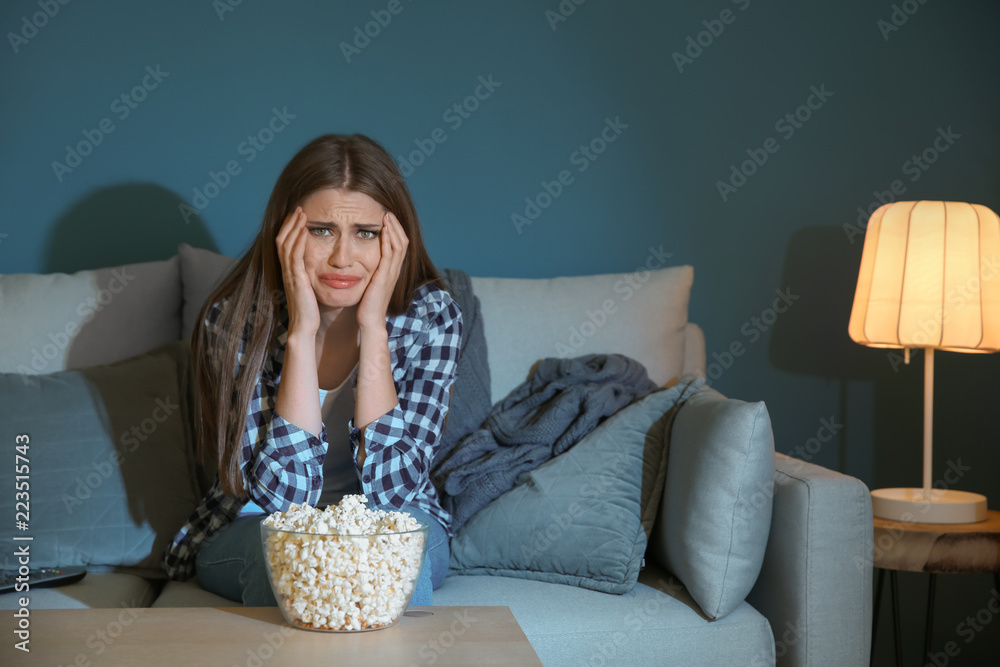 情绪激动的年轻女子深夜边看电视边吃爆米花