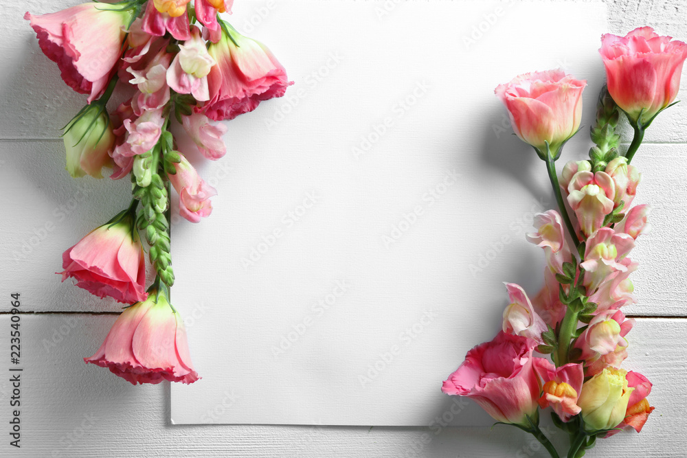 美丽的花朵和白色木桌上的空纸
