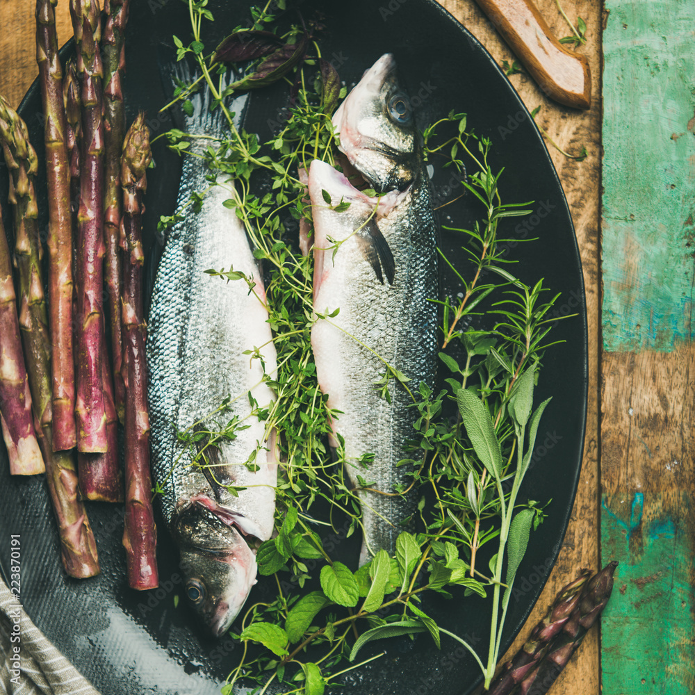 烹饪鱼晚餐。将生的未煮熟的海鲈与香草和蔬菜平铺在乡村窝上