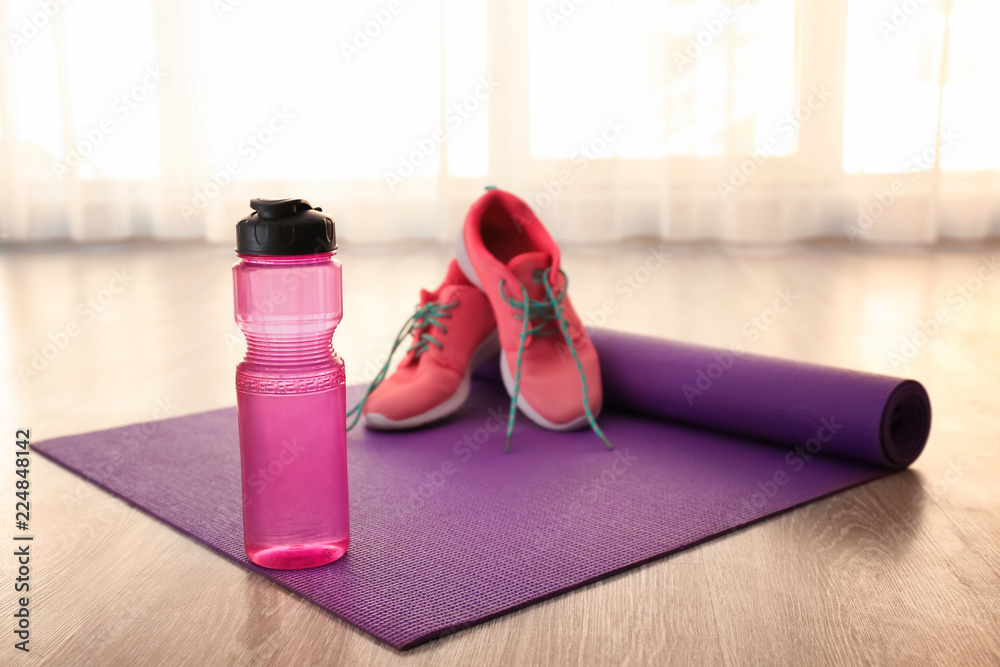 瑜伽垫、运动鞋和地板上的水瓶