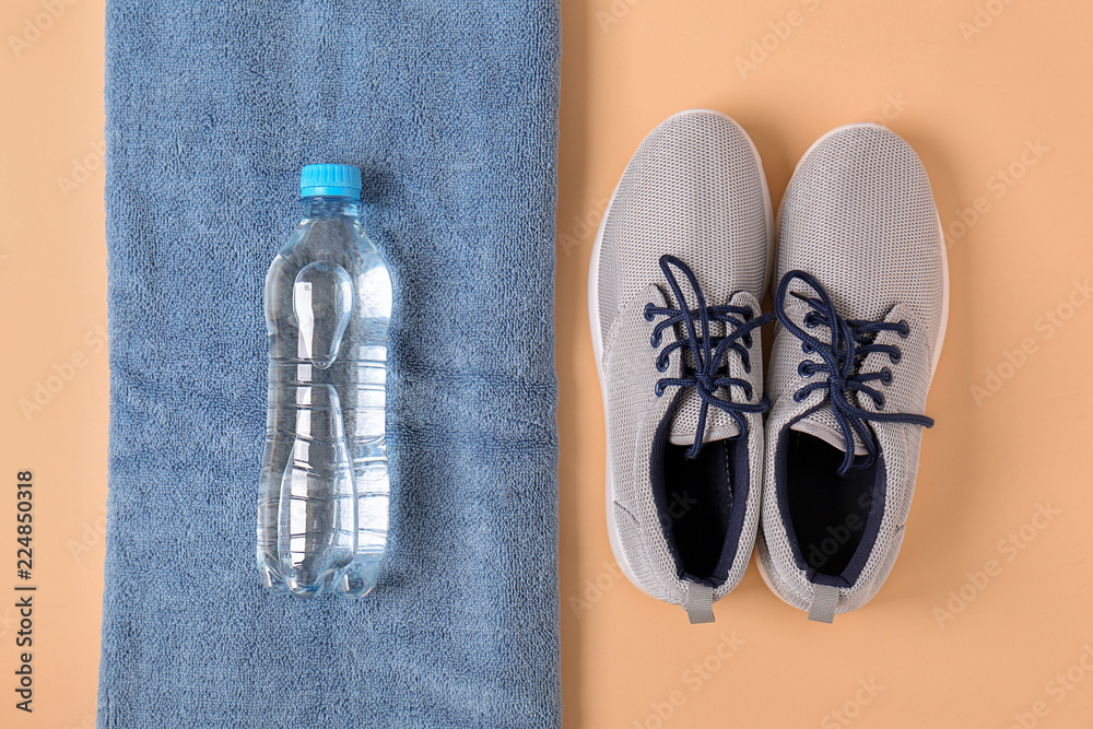 带运动鞋的干净软毛巾和彩色背景的水瓶