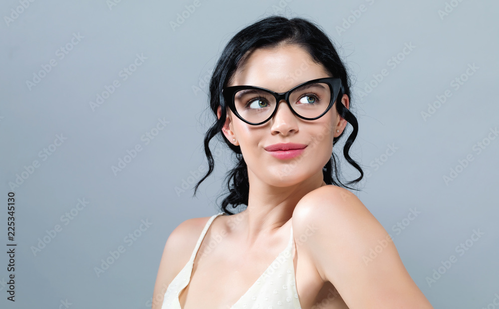 灰色背景下戴眼镜的年轻女子