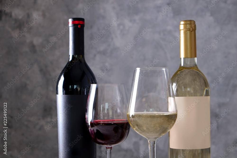 两瓶红白葡萄酒，混凝土墙背景上有哑光黑白空白标签。