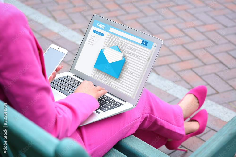 年轻的女商人拿着笔记本电脑在户外查看电子邮件