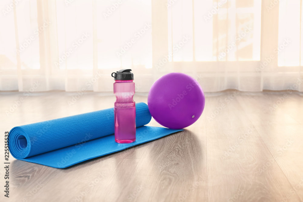 室内地板上有水瓶和球的瑜伽垫