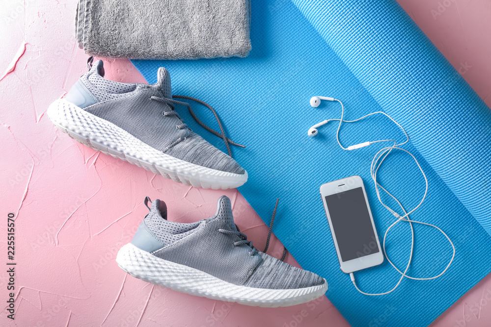 瑜伽垫、运动鞋、毛巾和彩色背景手机