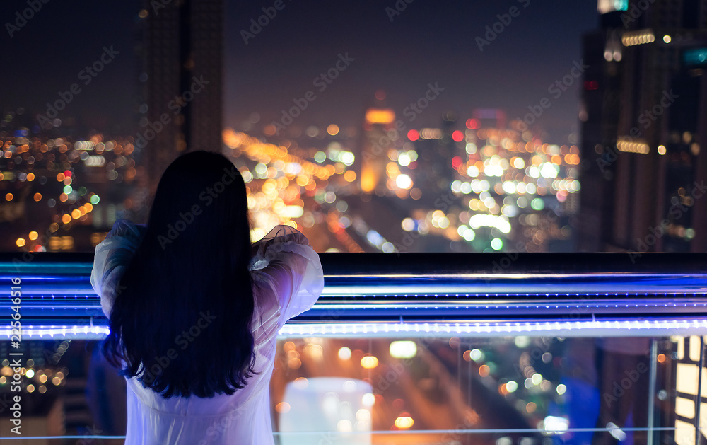 从阳台欣赏夜景的女人