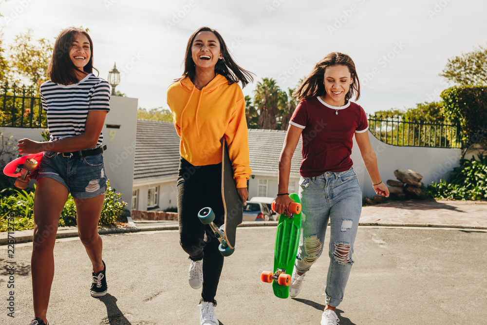 青少年女孩拿着滑板走在街上