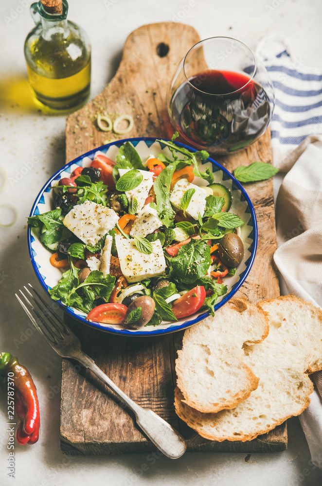 传统的自制希腊沙拉，配上菲塔奶酪、橄榄油和橄榄以及一杯红葡萄酒。