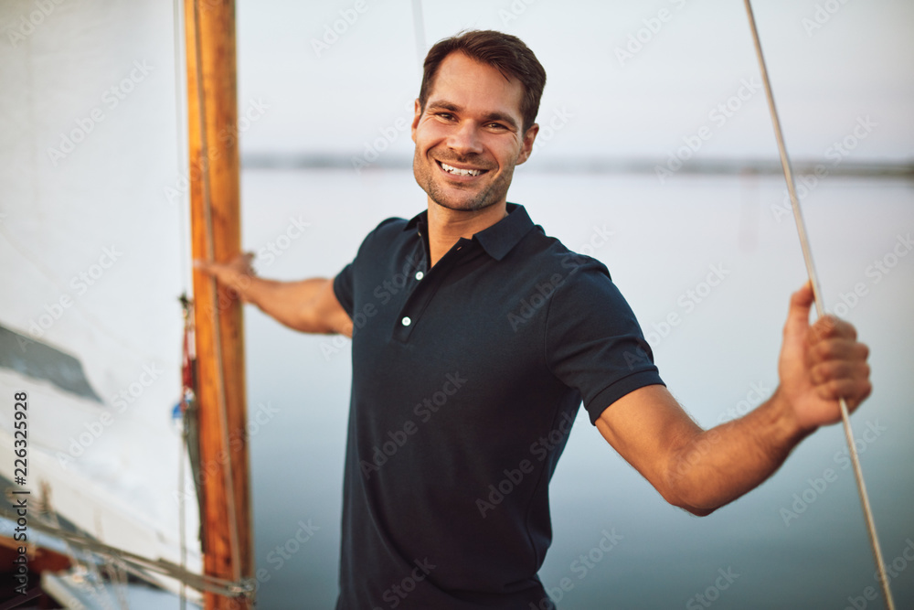 独自站在游艇甲板上微笑的年轻人