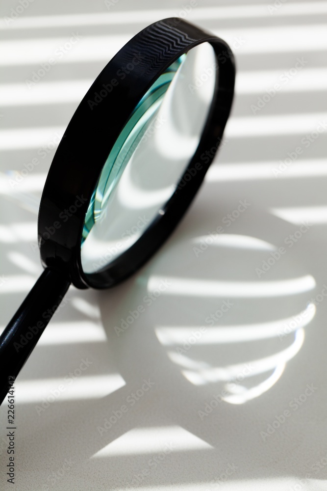 Magnifying Glass With Sun Shining On It Through Window Blinds