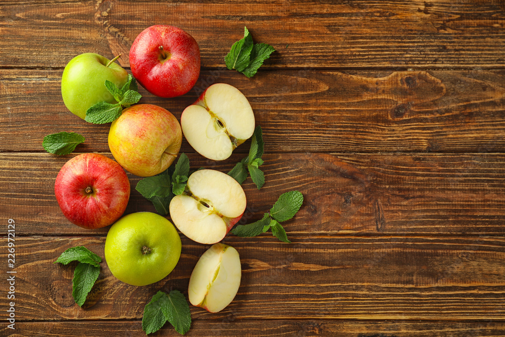 在木桌上用薄荷将新鲜成熟的苹果切开并整粒