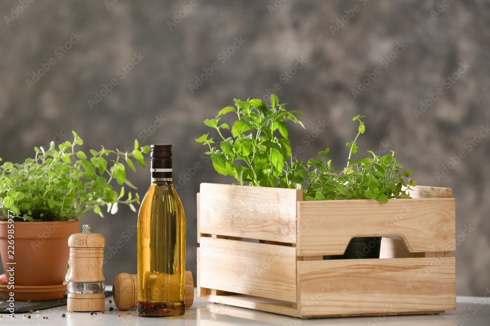 白色桌子上放着新鲜芳香草本植物的板条箱和锅