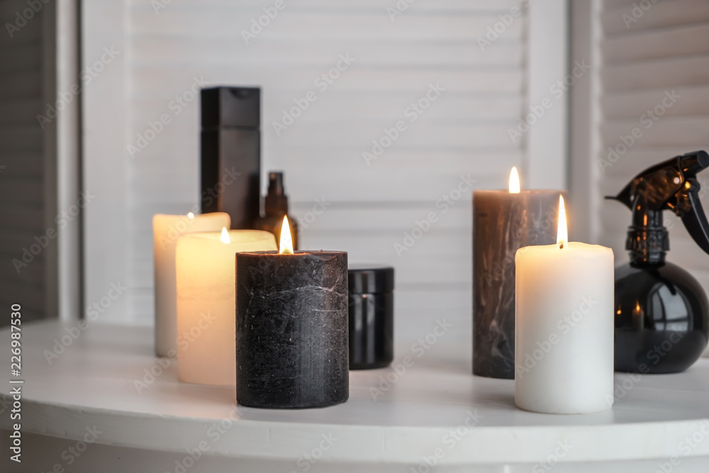 Burning candles with cosmetics on white table indoors