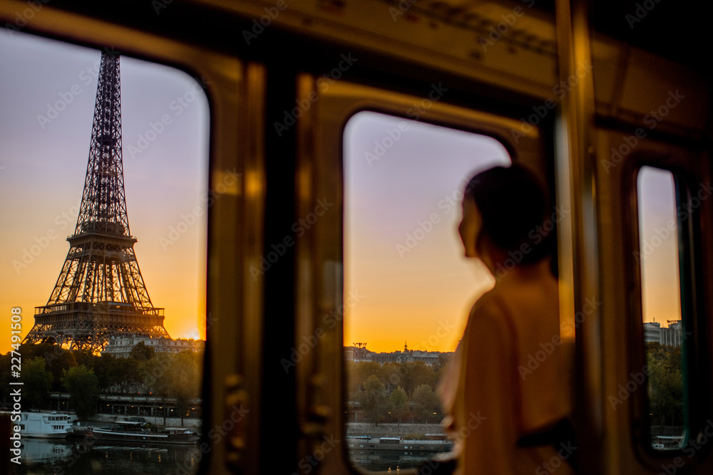 巴黎日出时，一名年轻女子从地铁列车上欣赏埃菲尔铁塔。伊玛