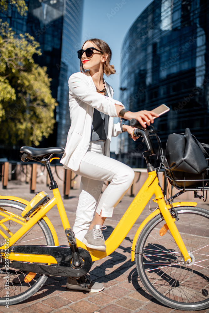 一位穿着白色西装、骑着自行车站在金融区w的时尚商务女性的肖像