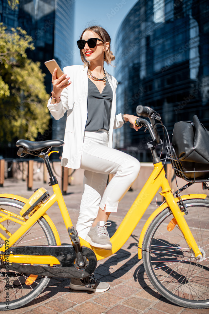 一位身穿白色西装、骑着自行车站在金融区的时尚商务女性的肖像