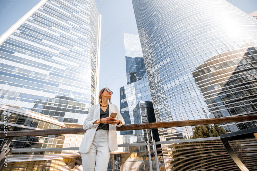 一位年轻的商业女性在户外的肖像，背景是高耸的摩天大楼