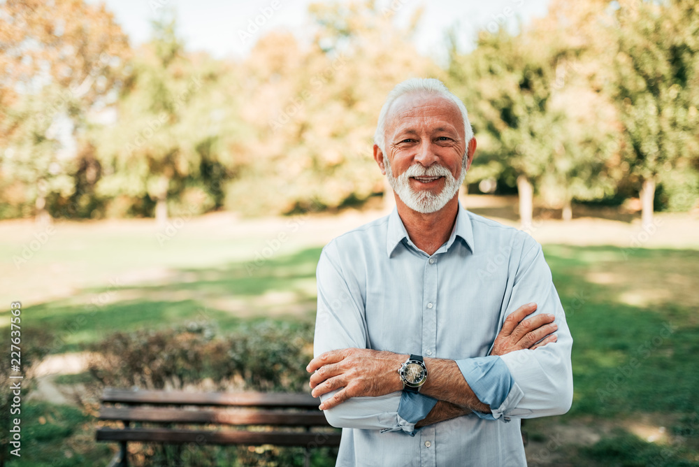 Portrait of a smiling older man in the park.
