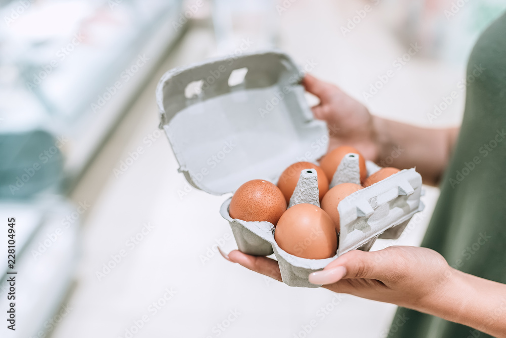 一个女孩拿着装有鸡蛋的纸箱的特写照片。