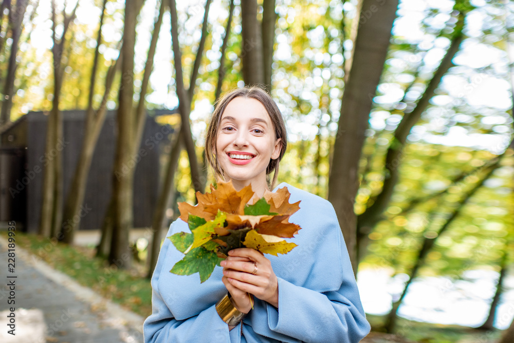 秋天森林里一位美丽的女人的画像，她在户外有五颜六色的叶子