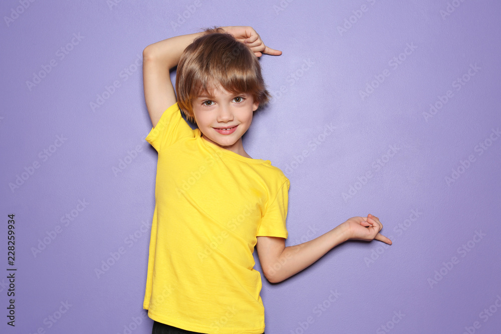 穿着t恤的小男孩指着彩色背景上的东西