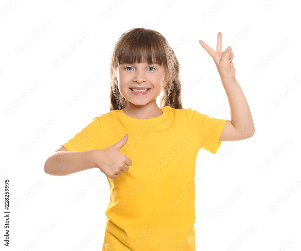 穿着t恤的小女孩在白底上竖起大拇指和胜利手势