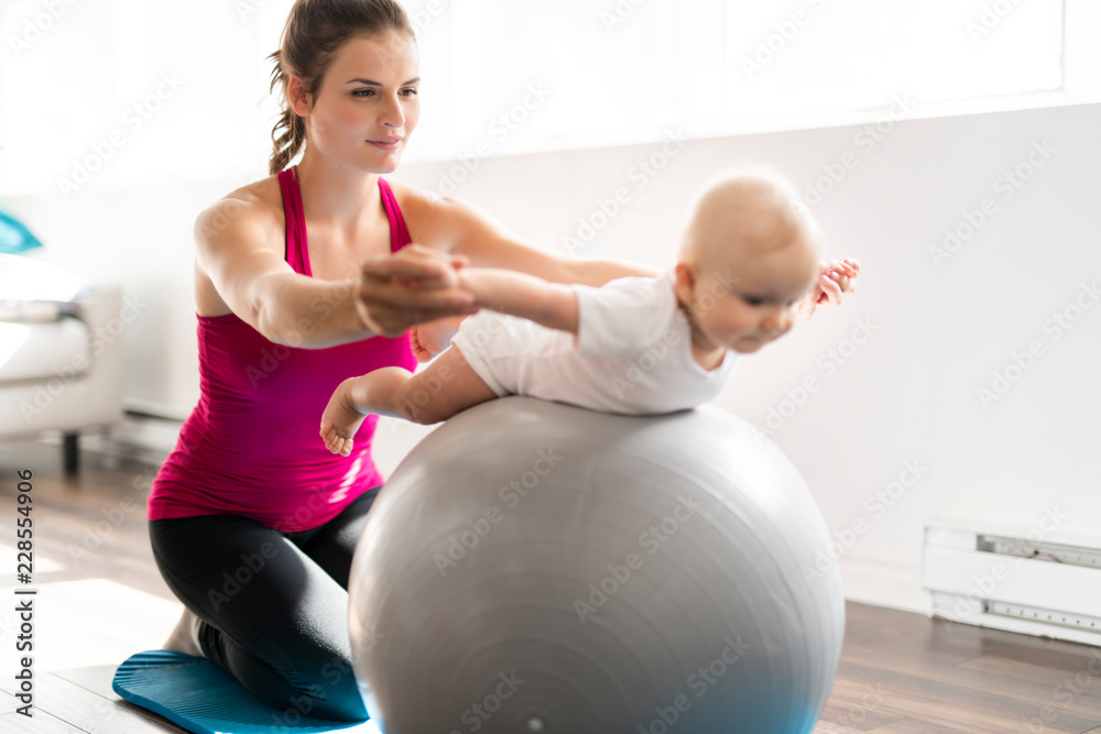 穿着运动服的美丽年轻母亲和她迷人的小宝宝在训练课上的肖像