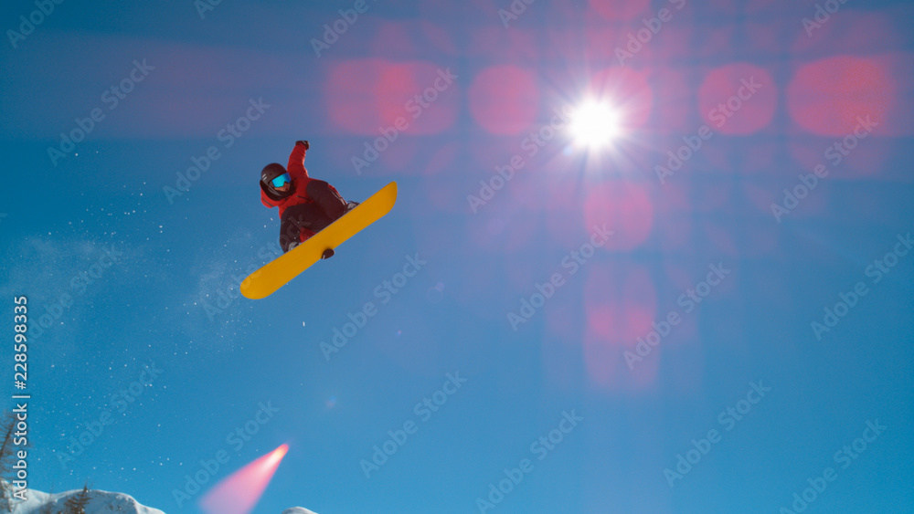 LENS FLARE：极限男子单板滑雪运动员从踢球者手中起飞并握住他的滑板