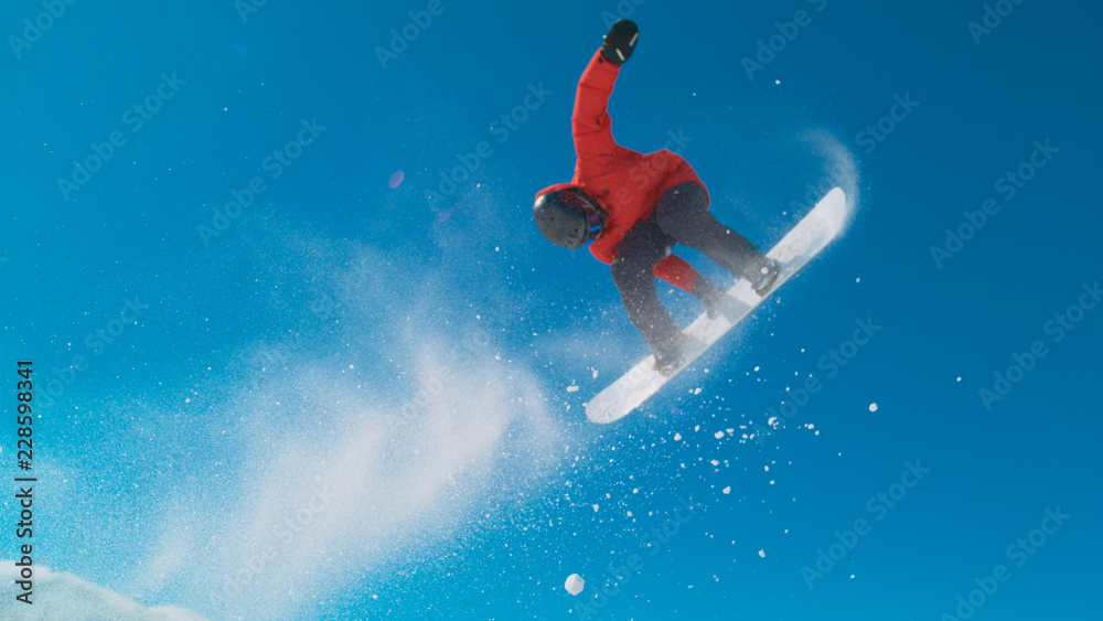 身穿红色冬季夹克的运动员滑雪并在空中表演技巧。