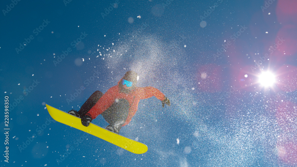 LENS FLARE明亮的阳光照射在单板滑雪运动员跳下踢球者身上，并表演了一个技巧