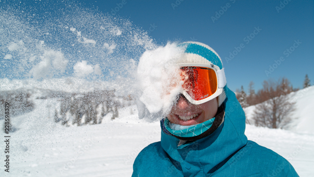 特写：戴着滑雪护目镜的兴奋女孩被雪球击中头部。