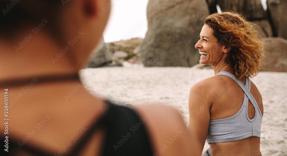 穿着健身服坐在海滩上的快乐女人