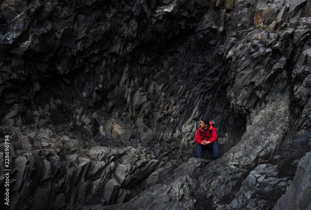 男性游客正在攀登冰岛黑沙滩的熔岩。