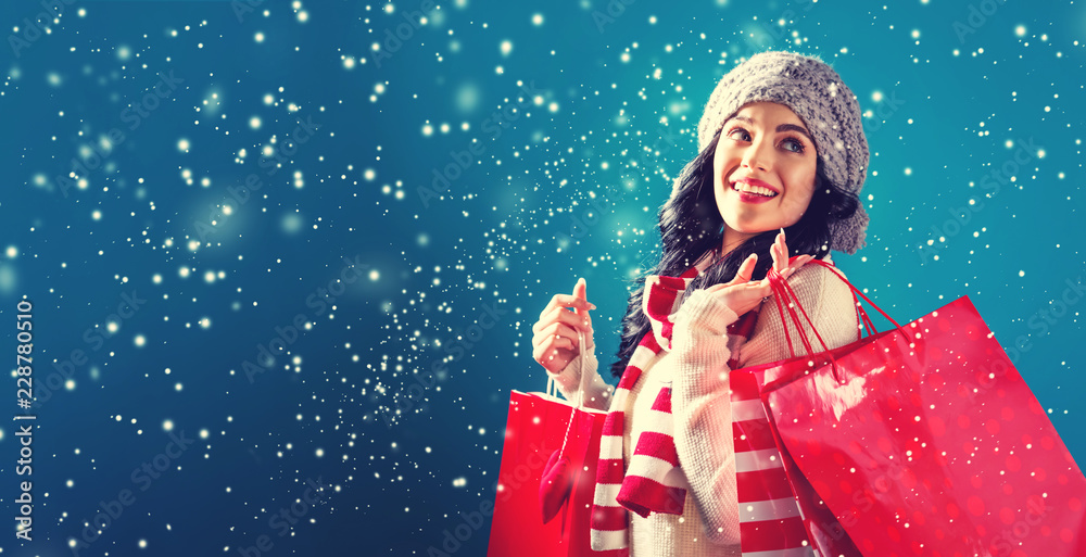 雪夜抱着购物袋的快乐年轻女子