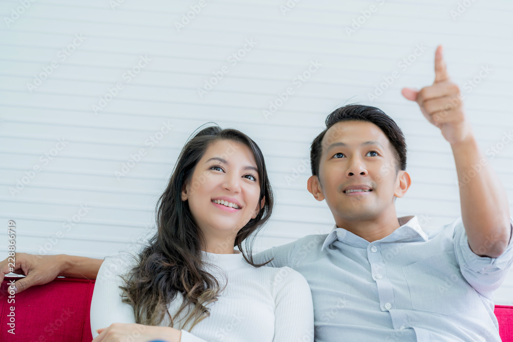 亚洲丈夫和高加索妻子一起看电视节目，带着幸福快乐的家庭观念