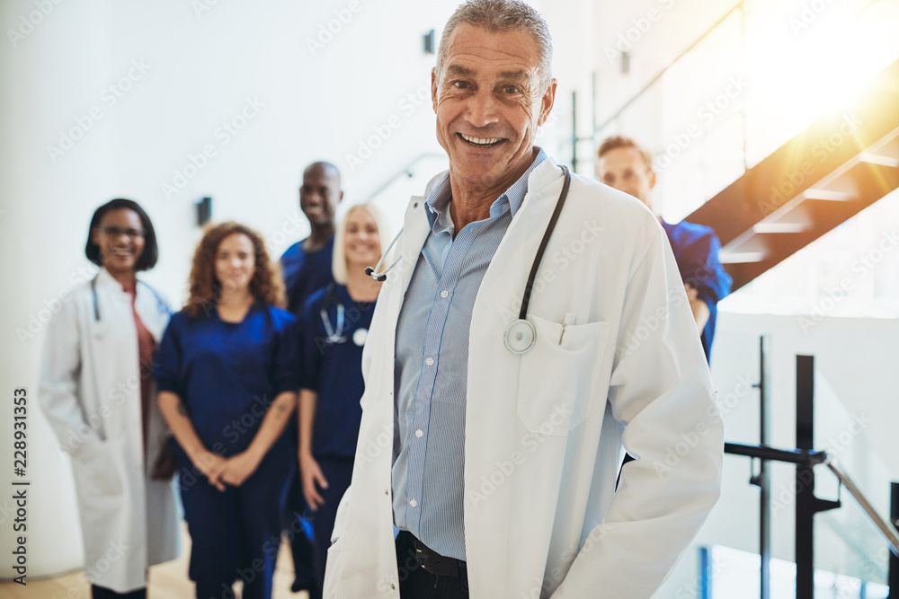 微笑的成熟医生和他的工作人员站在医院里