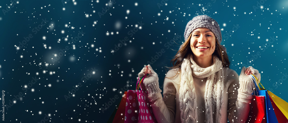雪夜抱着购物袋的快乐年轻女子