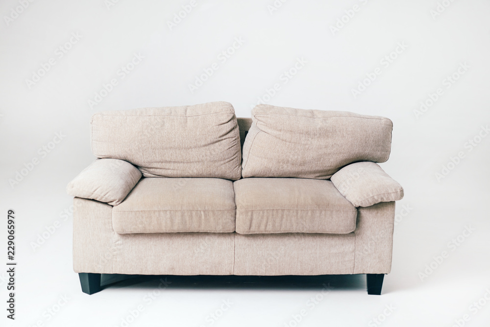 一个带枕头的灰色软沙发位于房间中央，白色背景。家具。国际